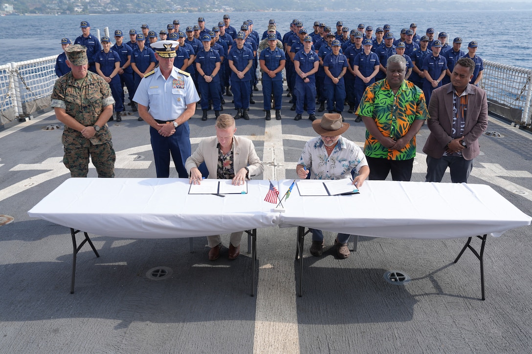 U.S. Chargé d'affaires and Solomon Islands Prime Minister Wale sign a bilateral maritime law enforcement agreement on the flight deck of Coast Guard Cutter Harriet Lane (WMEC 903) in Solomon Islands, July 28. 2026. During their patrol, the cutter's crew worked alongside Pacific Island Countries to combat illegal fishing activities and enhance maritime domain awareness. (U.S. Coast Guard photo, courtesy CGC Harriet Lane)