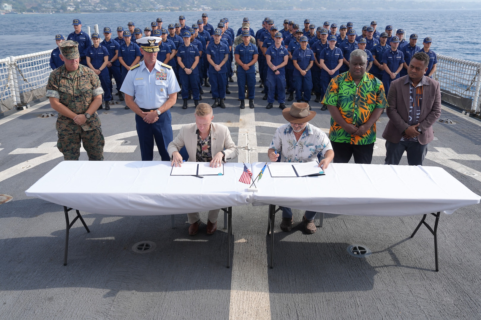 U.S. Chargé d'affaires and Solomon Islands Prime Minister Wale sign a bilateral maritime law enforcement agreement on the flight deck of Coast Guard Cutter Harriet Lane (WMEC 903) in Solomon Islands, July 28. 2026. During their patrol, the cutter's crew worked alongside Pacific Island Countries to combat illegal fishing activities and enhance maritime domain awareness. (U.S. Coast Guard photo, courtesy CGC Harriet Lane)