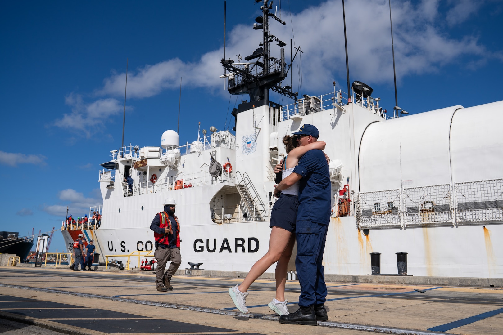 A Coast Guardsman assigned to Coast Guard Cutter Harriet Lane (WMEC 903) embraces a loved one on a pier at Joint Base Pearl Harbor-Hickam, Honolulu, Hawaii, Aug. 12, 2026. The Harriet Lane completed a 75-day patrol in support of Operation Blue Pacific. (U.S. Coast Guard photo by Petty Officer 3rd Class Avery Tibbets)