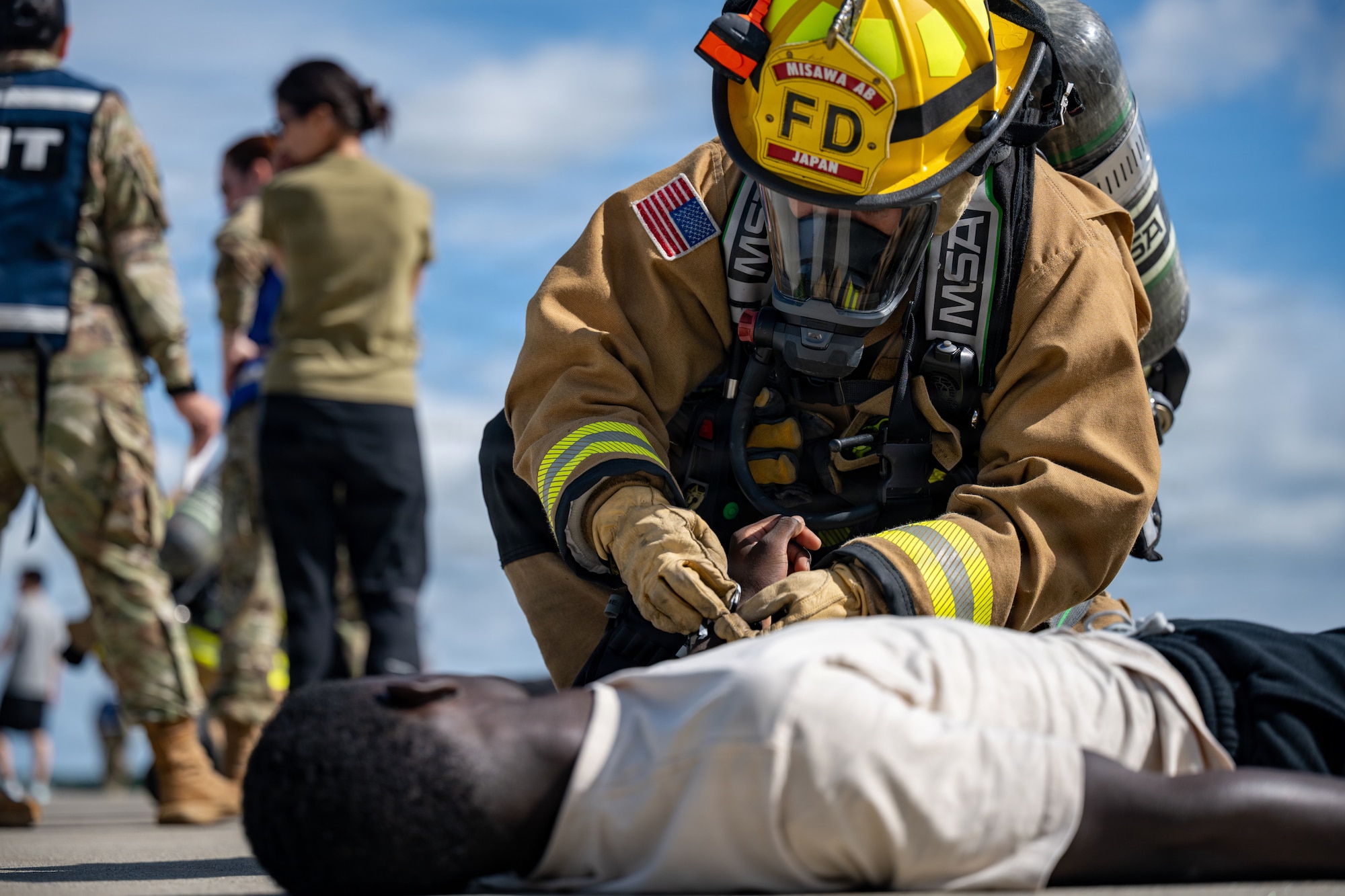 U.S. Air Force Airman 1st Class Paul John Benedictos, 35th Fighter Wing Civil Engineer Squadron firefighter, marks a simulated patient as deceased with a wristband during an aircraft mass casualty exercise.