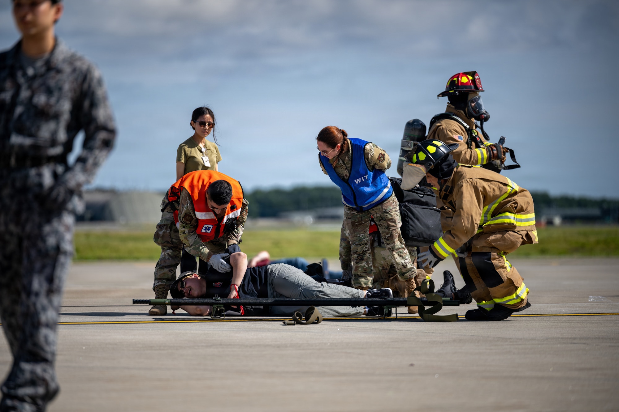 U.S. Airmen assigned to the 35th Fighter Squadron transfer a simulated patient to a stretcher for transport during an aircraft mass casualty exercise.
