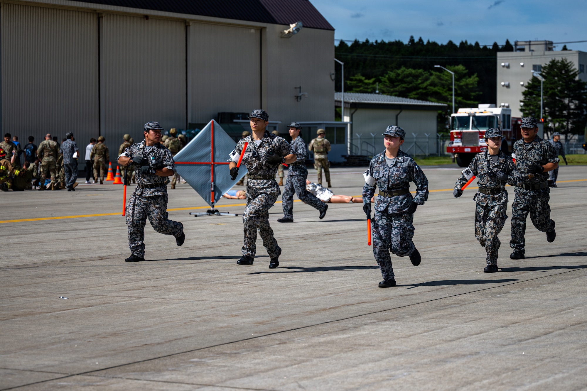 Japan Air Self-Defense Force (JASDF) airmen assigned to the 3rd Air Wing run to secure the perimeter of an emergency scene during an aircraft mass casualty exercise.