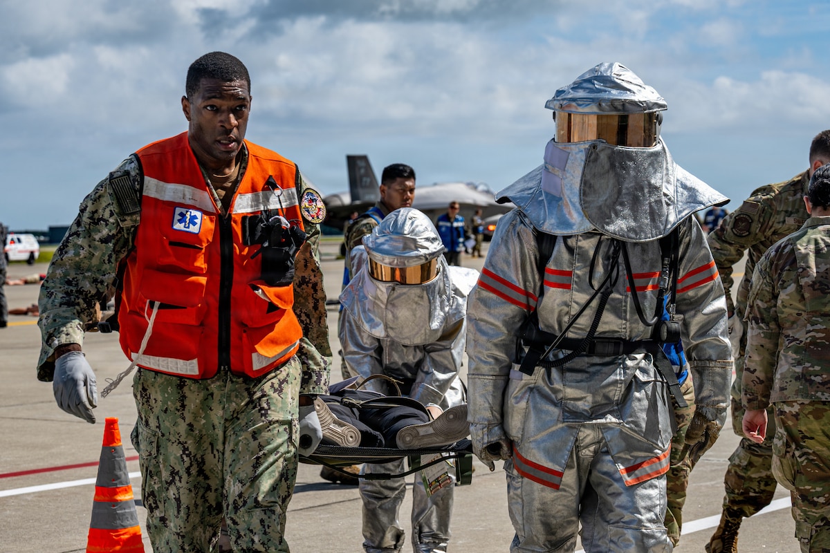 A U.S. Navy hospital corpsmen assigned to Naval Air Facility Misawa and Japan Air Self-Defense Force airmen assigned to the 3rd Air Wing carry a simulated patient on a stretcher during an aircraft mass casualty exercise.