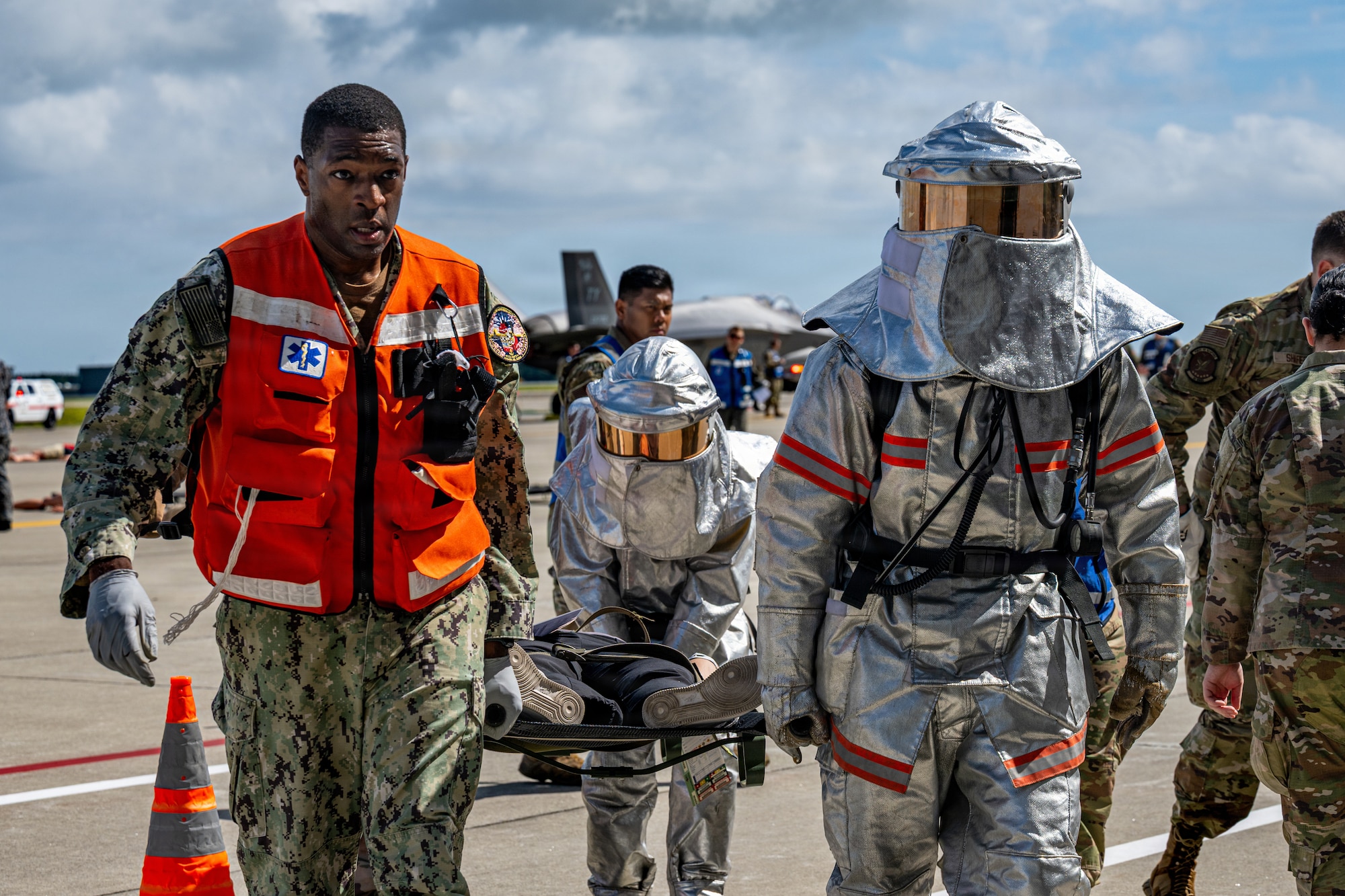 A U.S. Navy hospital corpsmen assigned to Naval Air Facility Misawa and Japan Air Self-Defense Force airmen assigned to the 3rd Air Wing carry a simulated patient on a stretcher during an aircraft mass casualty exercise.