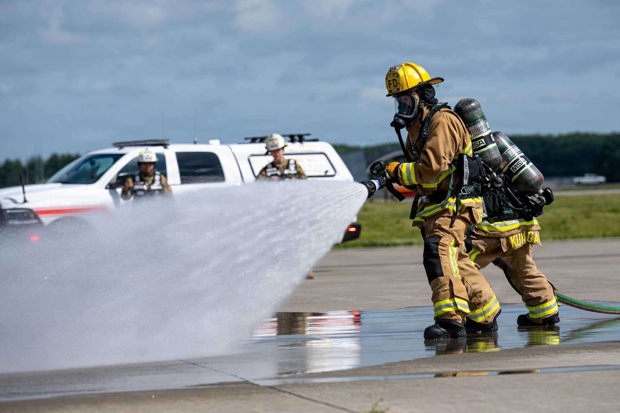 Migaku Esashika, left, and Tadakatsu Kumagai, 35th Fighter Wing Civil Engineer Squadron firefighters, respond to a simulated crashed aircraft during an aircraft mass casualty exercise.