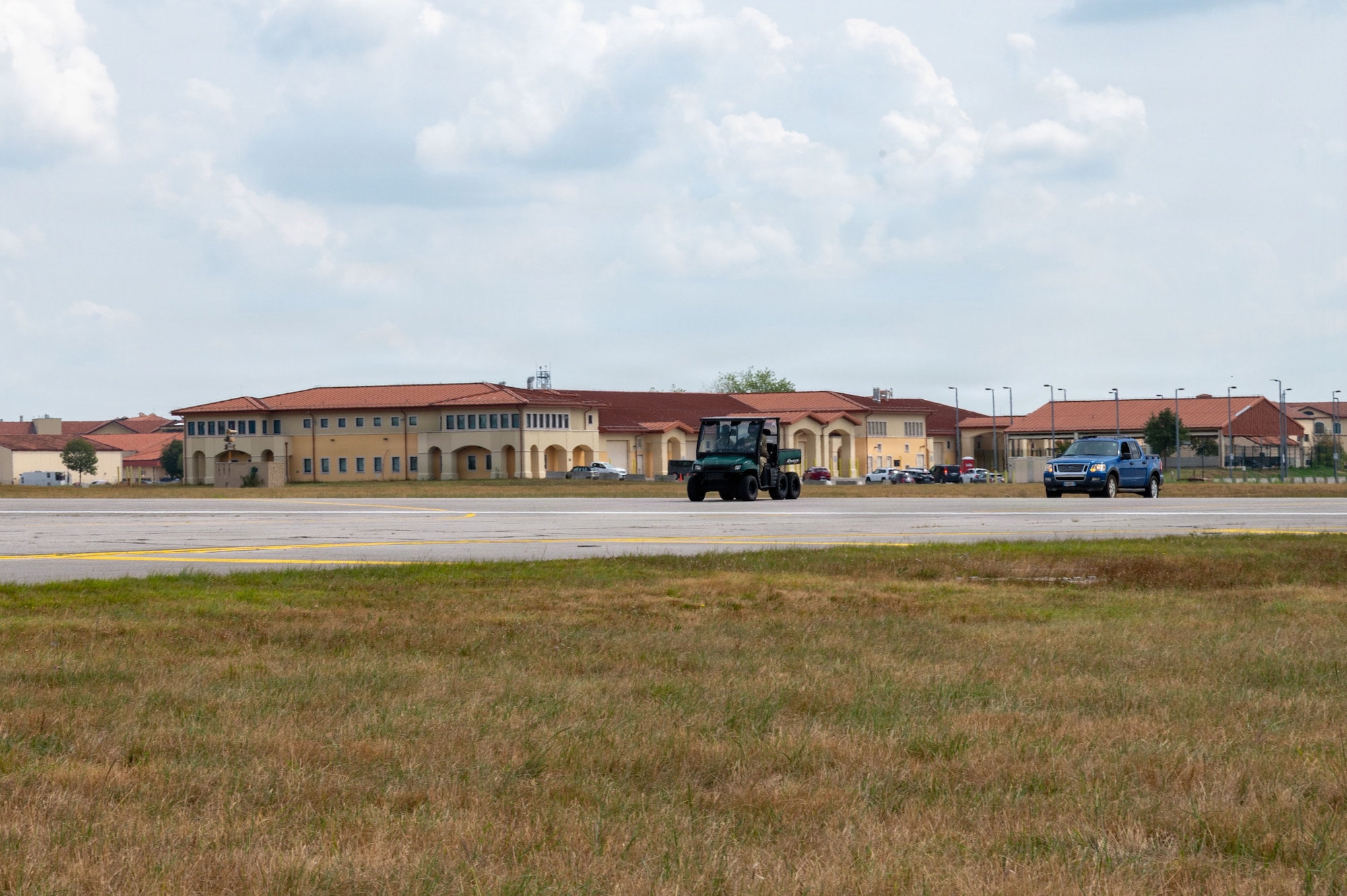 Two cars drive across a runway
