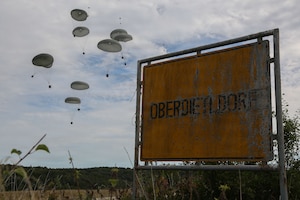 Supply boxes connected to parachutes descend to the ground after being dropped from an aircraft.