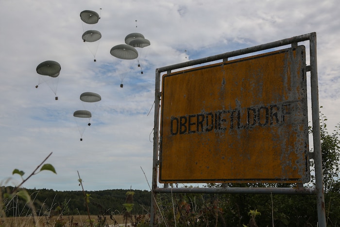 Supply boxes connected to parachutes descend to the ground after being dropped from an aircraft.