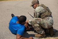 U.S. Air Force Tech. Sgt. Joel Ayala, assigned to the 103rd Security Forces Squadron, Connecticut Air National Guard, assists a role player during a simulated emergency response scenario at the Combined Arms Collective Training Facility at Fort McCoy, Wisconsin, Aug. 25, 2026.
