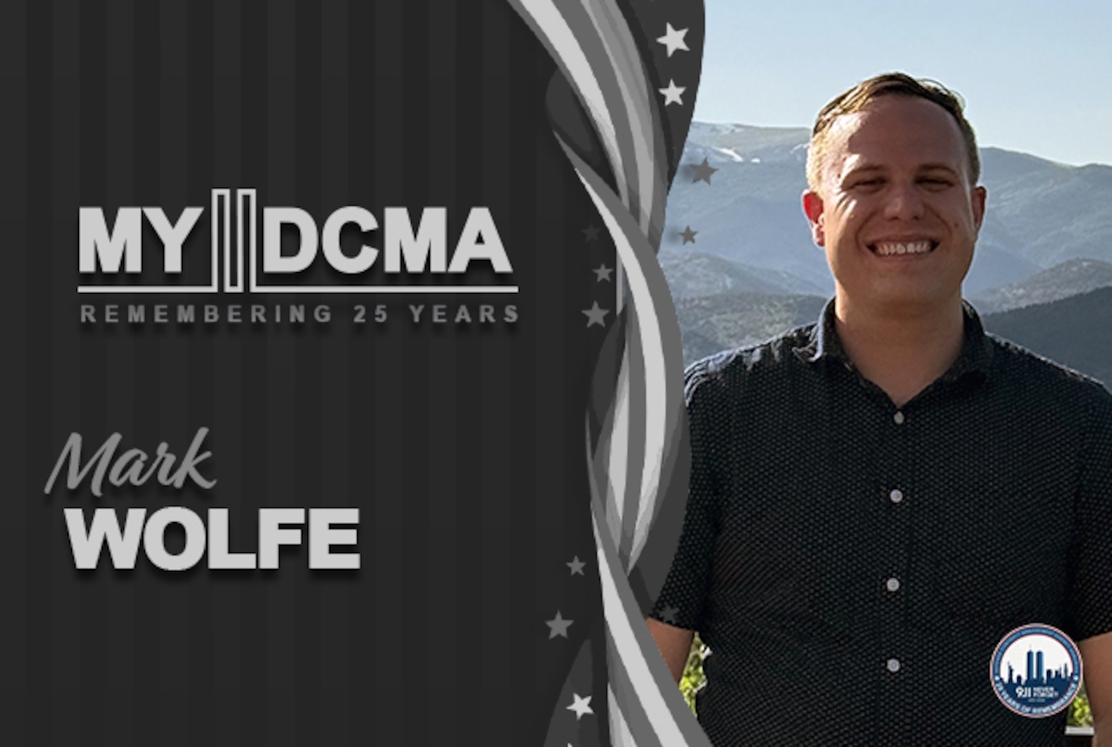 Smiling man wearing a black shirt stands in front of mountains