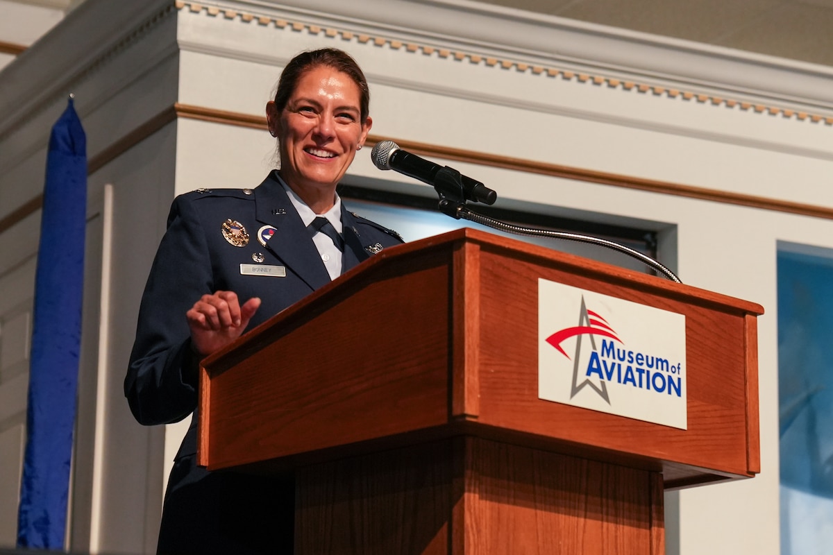 a colonel smiles while standing behind a podium