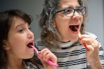 Woman and a child brushing their teeth