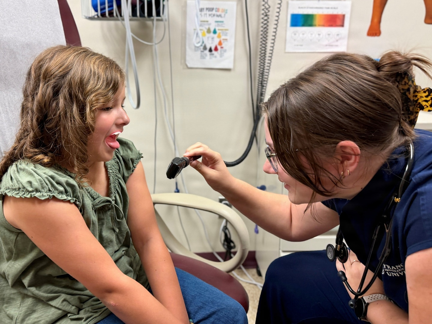 A second-year physician assistant student examines a 9-year-old patient's throat during a pediatric clinical training encounter