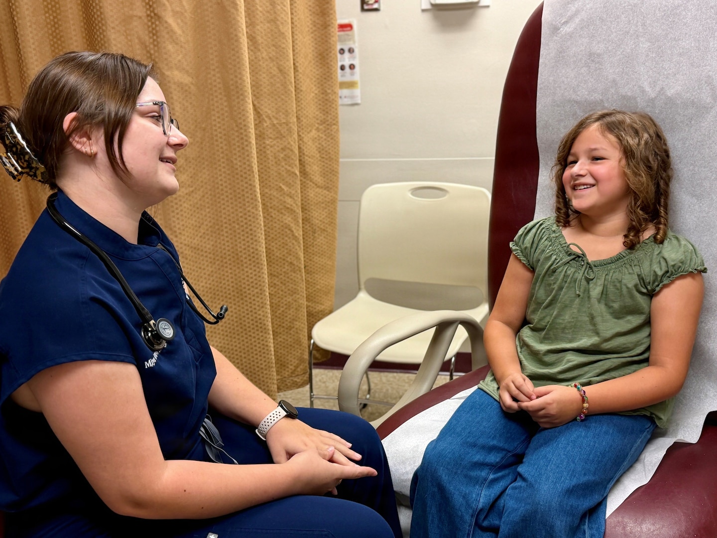 A physician assistant student talks with a 9-year-old patient during a pediatric clinical training encounter.