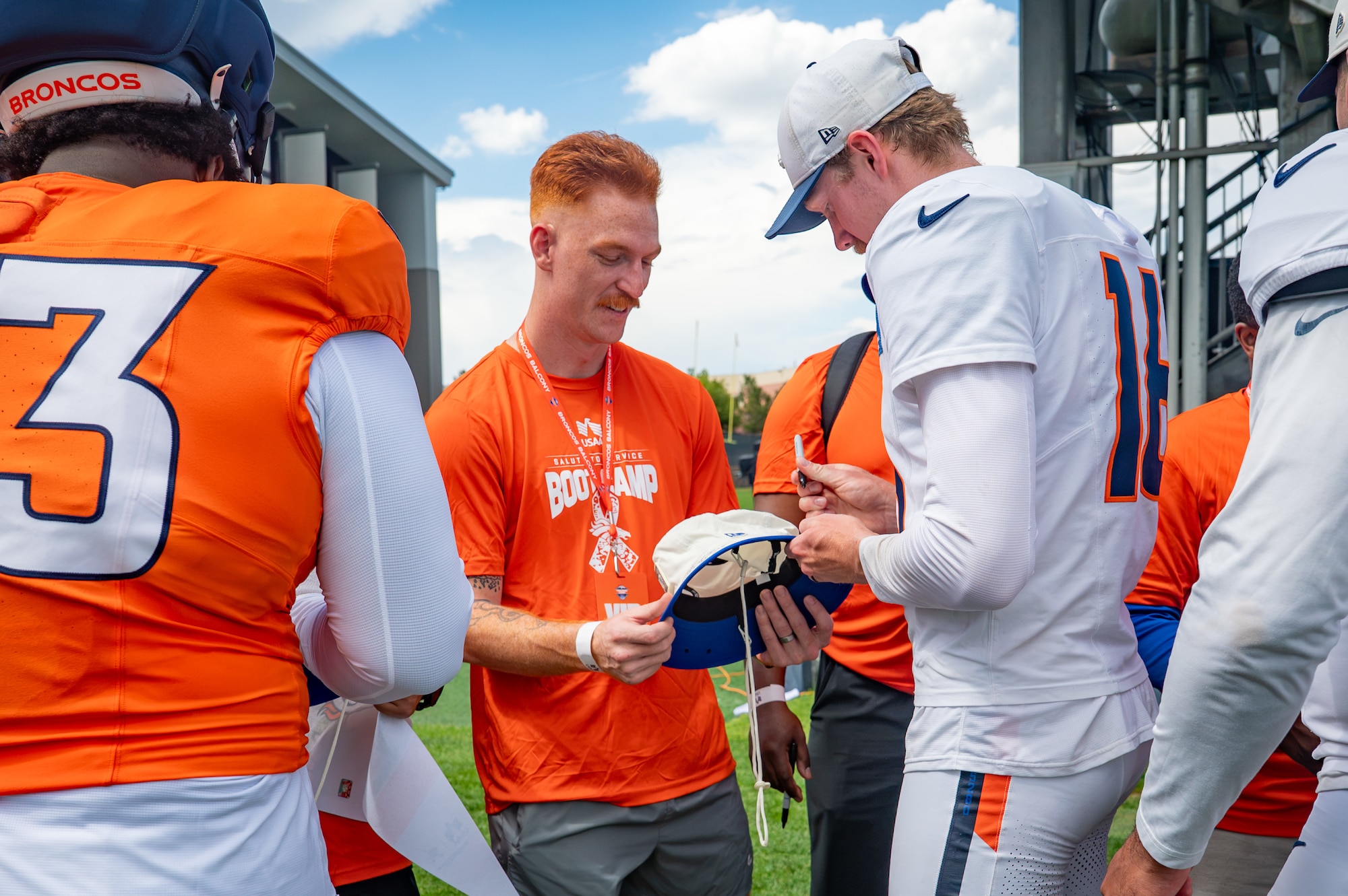 U.S. Space Force Tech. Sgt. Parker Martin, 62nd Cyber Squadron tactical developer, receives an autograph from Denver Broncos players during the USAA Salute to Service Boot Camp