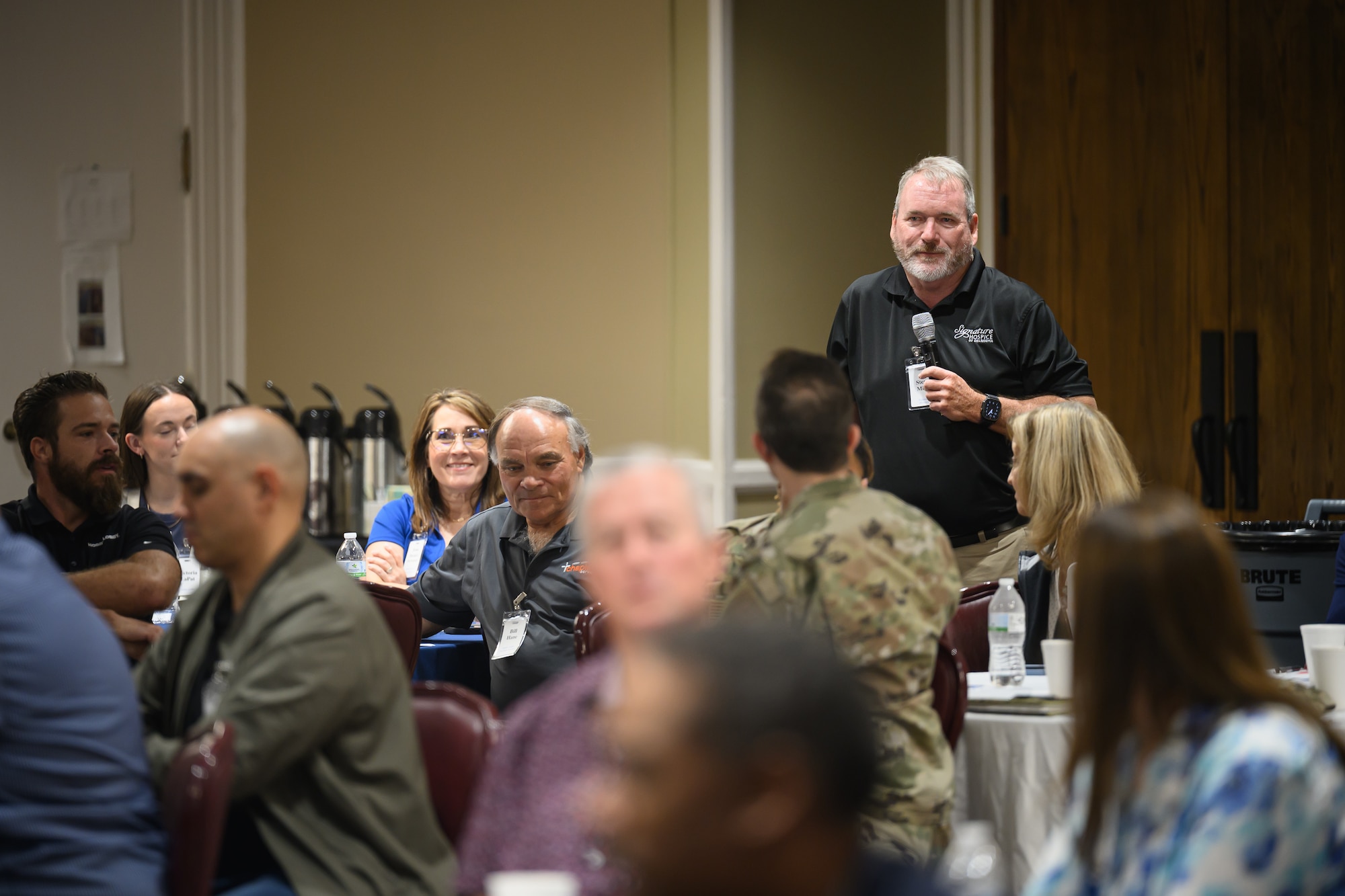 Uniformed and non-uniformed personnel gather at tables