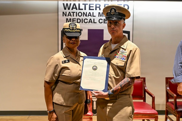 Senior Chief Hospital Corpsman Thomas Riggs, assigned to Navy Medicine Readiness and Training Command (NMRTC) Bethesda, poses for a photo with Presiding officer Capt. Toni McCrae (Retired) during his retirement ceremony at Walter Reed National Military Medical Center, August 20, 2026. NMRTC Bethesda mission is to maximize warfighter performance through optimized medical readiness tailored to operational requirements; enhance the readiness of the medical force to sustain expeditionary medical capability; and train and develop the Navy Medicine Force. (U.S. Navy photo Mass Communication Specialist Second Class Alec Kramer)