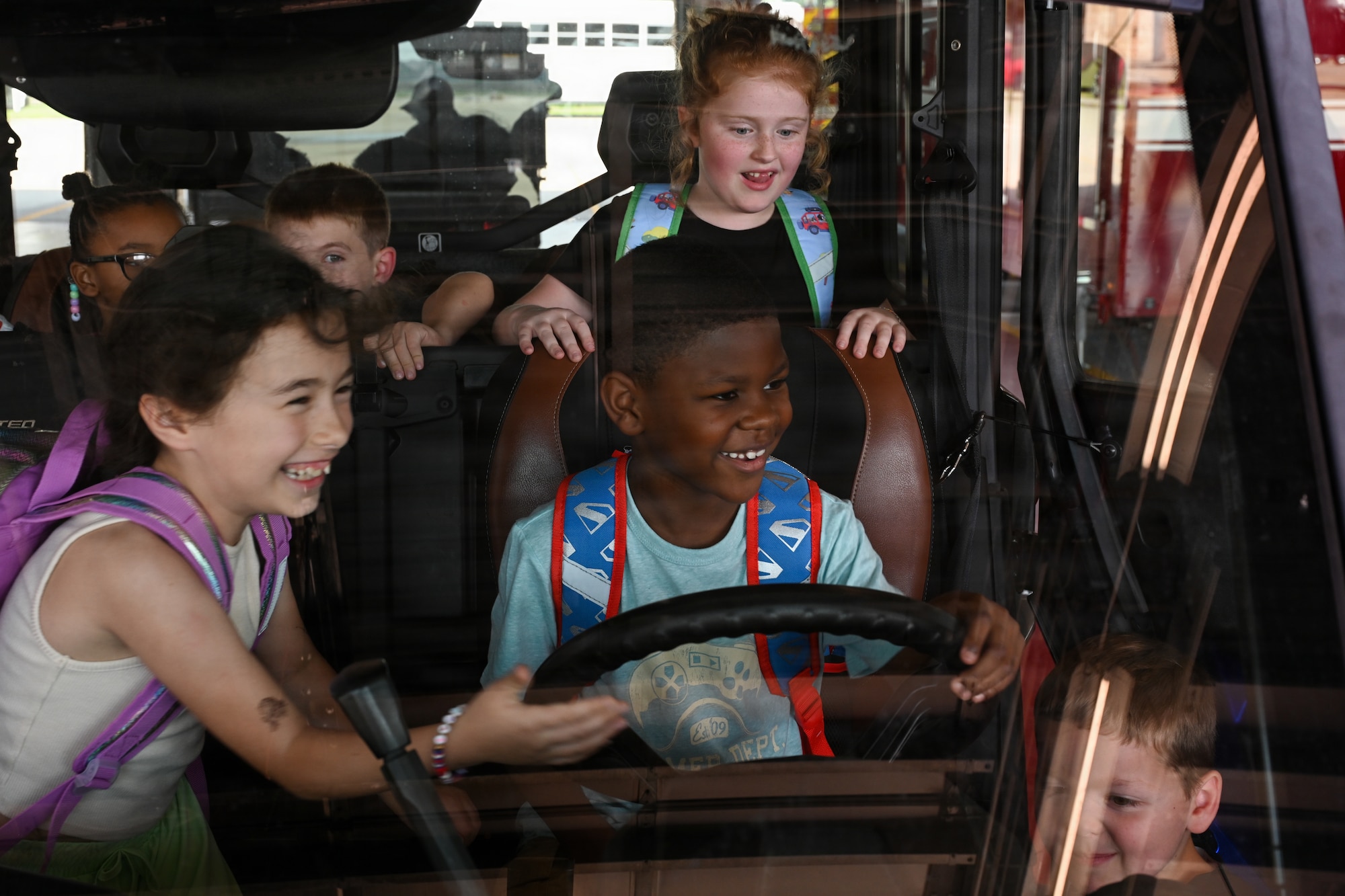 Military children exploring the cab of a military vehicle.