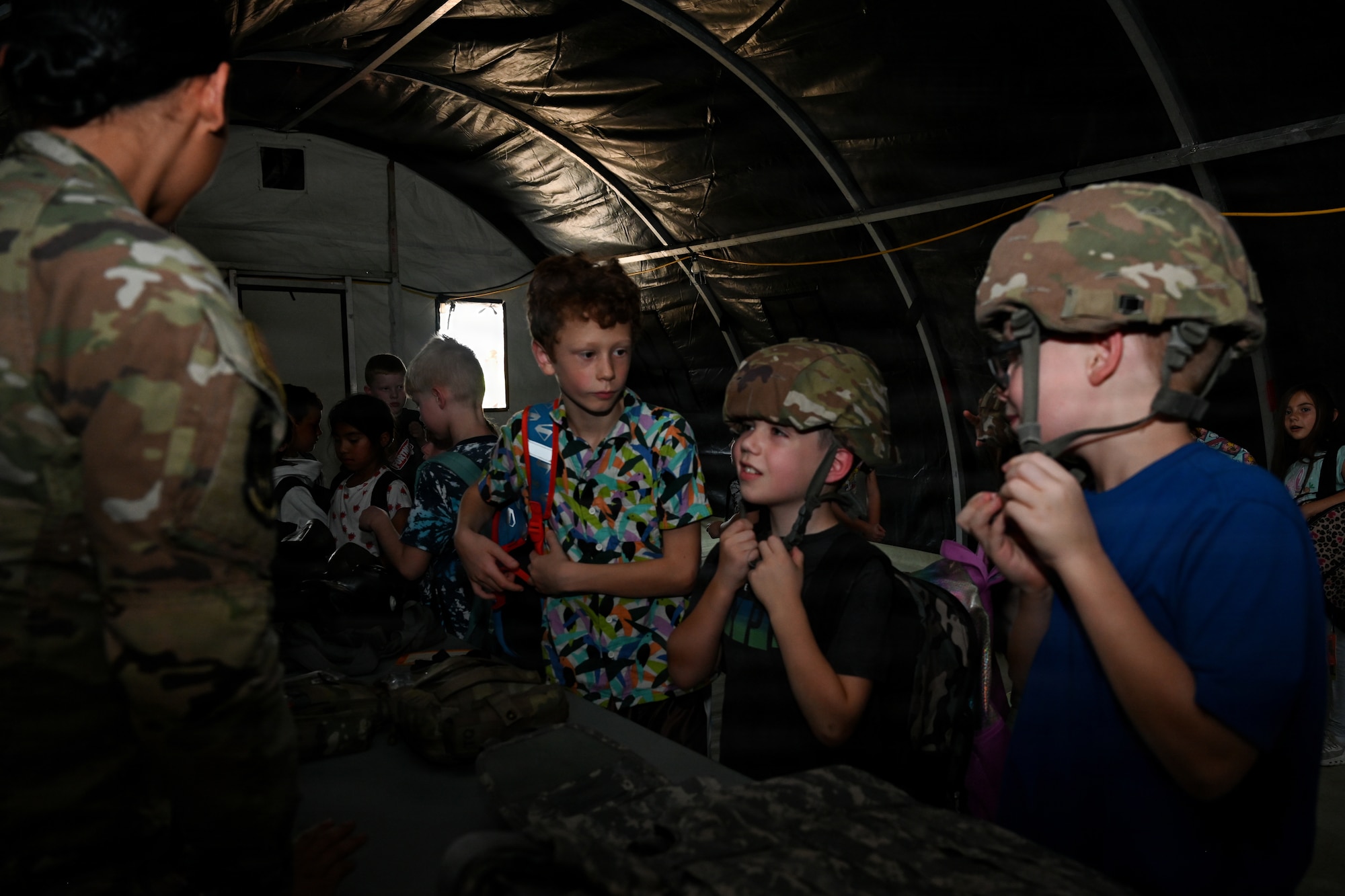 Military children trying on military issued gear during a mock deployment.