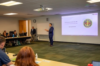 Cmdr. Jacob Cole, the chief health informatics officer assigned to  U.S. Navy Bureau of Medicine and Surgery, gives remarks during the Navy Operational Medicine Information Technology & Fielding Summit in Chesapeake, Virginia, Aug. 24, 2026. The five-day summit, held at the CACI Building in Chesapeake, brings together senior leaders from BUMED, Fleet commands, Naval Information Warfare Centers, and Joint Operational Medicine Information Systems teams. The primary objective was to deliver agile, trained, and certified medical units to support the Fleet, Fleet Marine Force and expeditionary medical facilities. (U.S. Navy photo by Mass Communication Specialist 2nd Class Levi Decker)