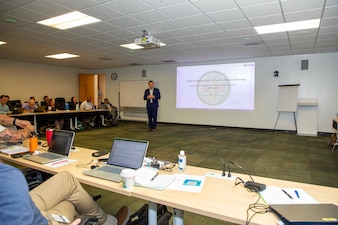 Cmdr. Jacob Cole, the chief health informatics officer assigned to  U.S. Navy Bureau of Medicine and Surgery, discusses health information data during the Navy Operational Medicine Information Technology & Fielding Summit in Chesapeake, Virginia, Aug. 24, 2026. The five-day summit, held at the CACI Building in Chesapeake, brings together senior leaders from BUMED, Fleet commands, Naval Information Warfare Centers, and Joint Operational Medicine Information Systems teams. The primary objective was to deliver agile, trained, and certified medical units to support the Fleet, Fleet Marine Force and expeditionary medical facilities. (U.S. Navy photo by Mass Communication Specialist 2nd Class Levi Decker)