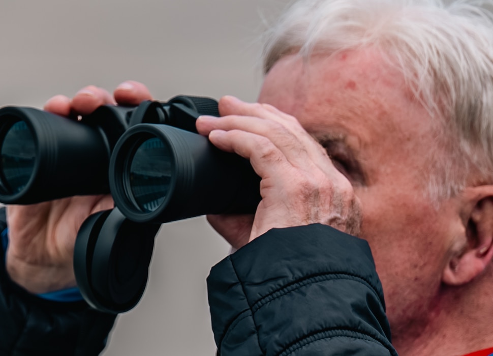 A spectator of Airshow London 2026 views performing aircraft through binoculars at London, Ontario, Aug. 22, 2026. The airshow has been voted Best Air Show in North America for the past four years in a row. (U.S. Air Force photo by Airman 1st Class Emma Wright)