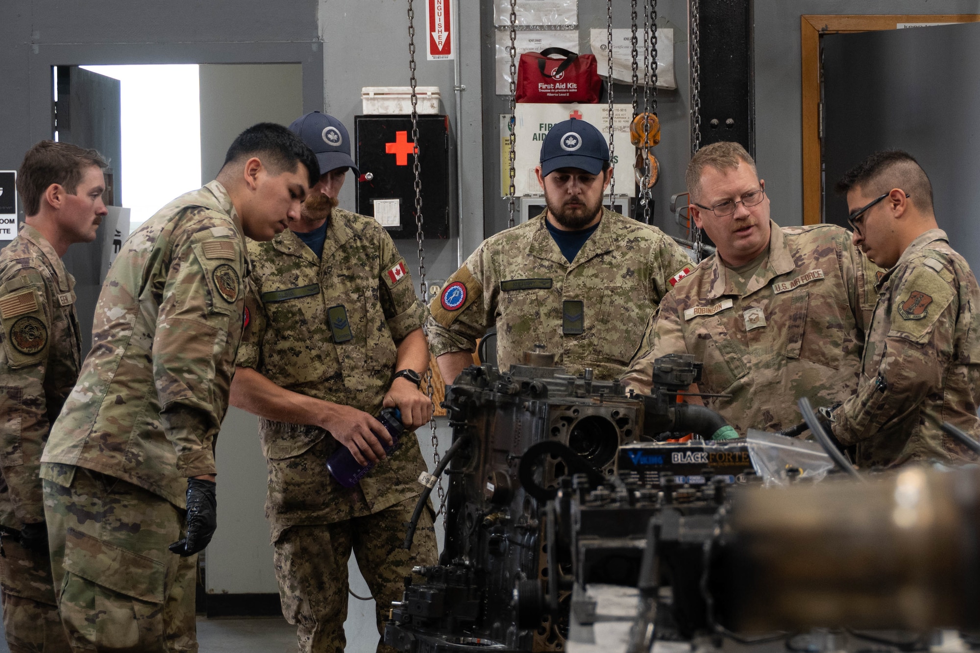 U.S. Air Force Airmen of the 185th Civil Engineering Squadron, Iowa National Guard, and Royal Canadian Air Force airmen work around an engine