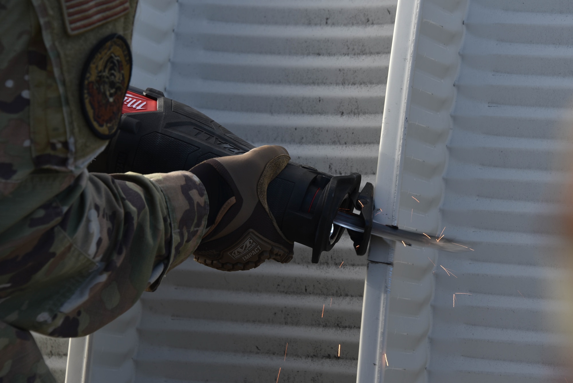 An Airman uses a reciprocating saw to cut apart an aluminum gazebo