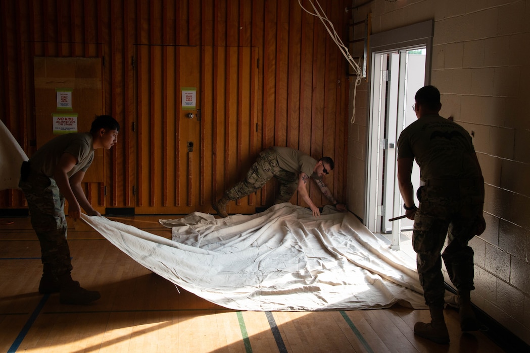 Airmen of the 185th Civil Engineering Squadron, Iowa National Guard, lay a protective cloth on a wooden floor