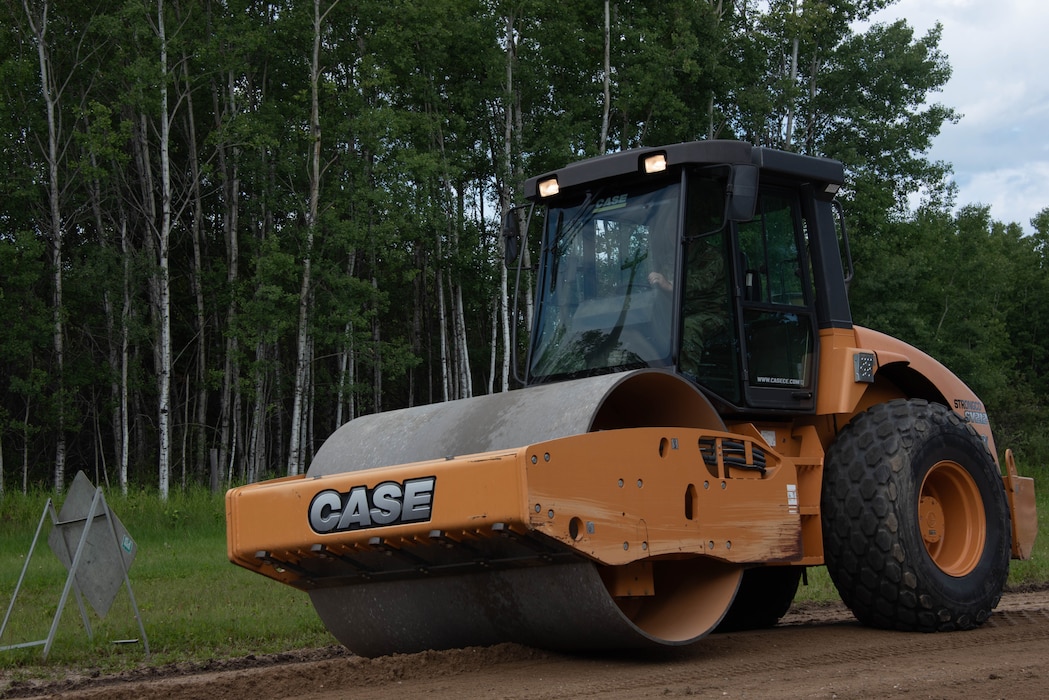 A road roller is driven on a dirt road.