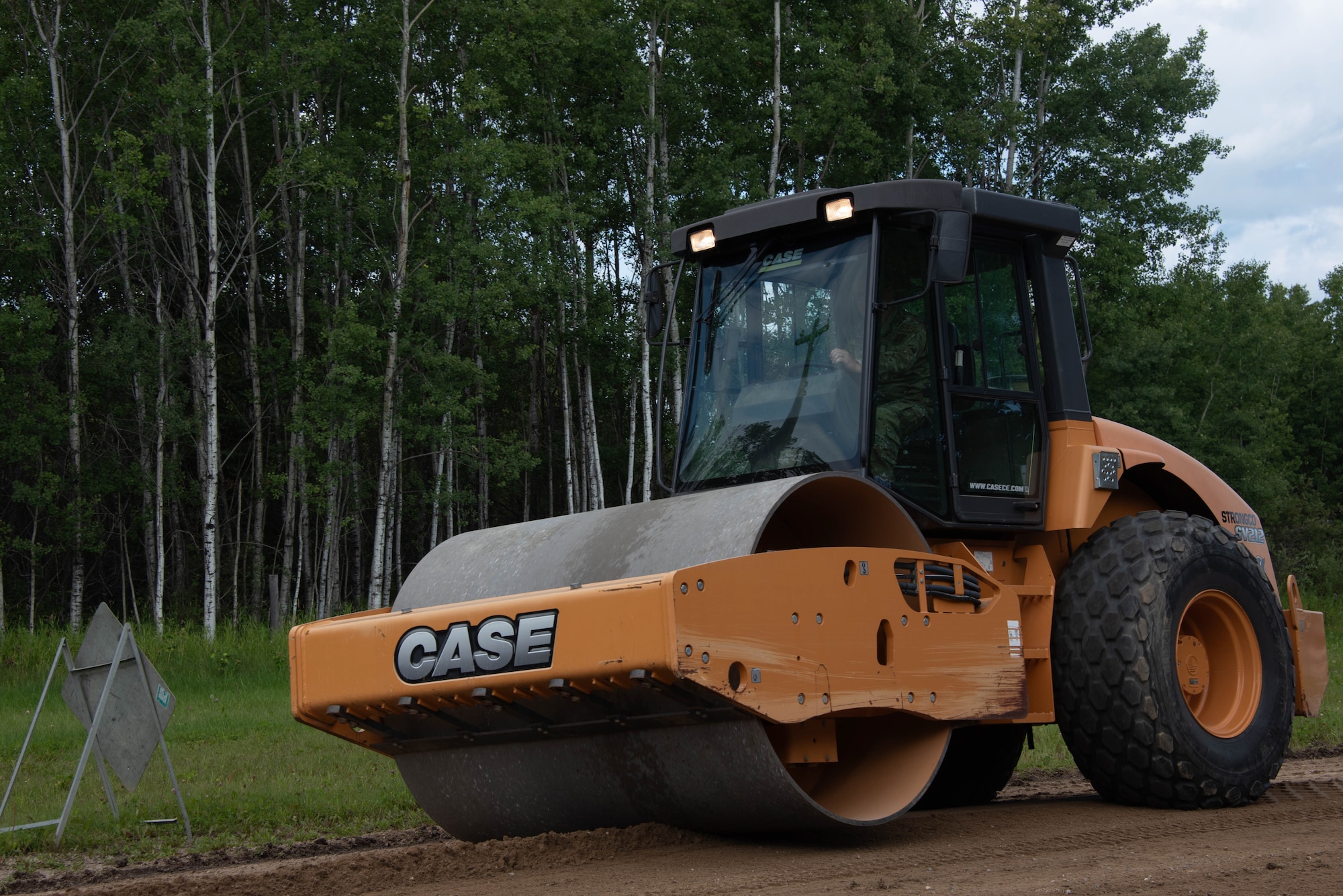 A road roller is driven on a dirt road.