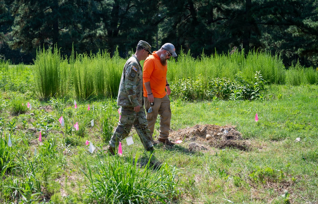 A Soldier and man look at an excavation site.