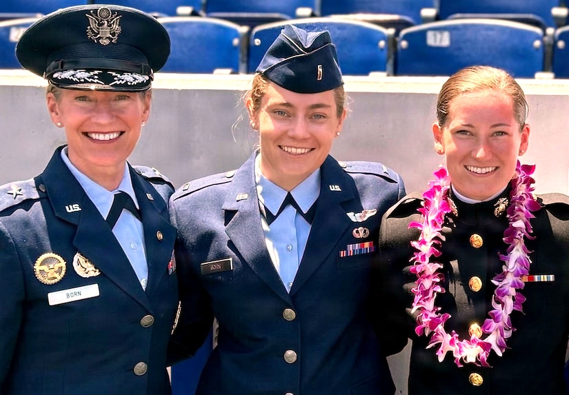 Three women in formal military uniforms pose for a photo.