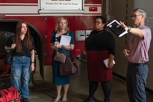 A group stands next to a fire engine indoors
