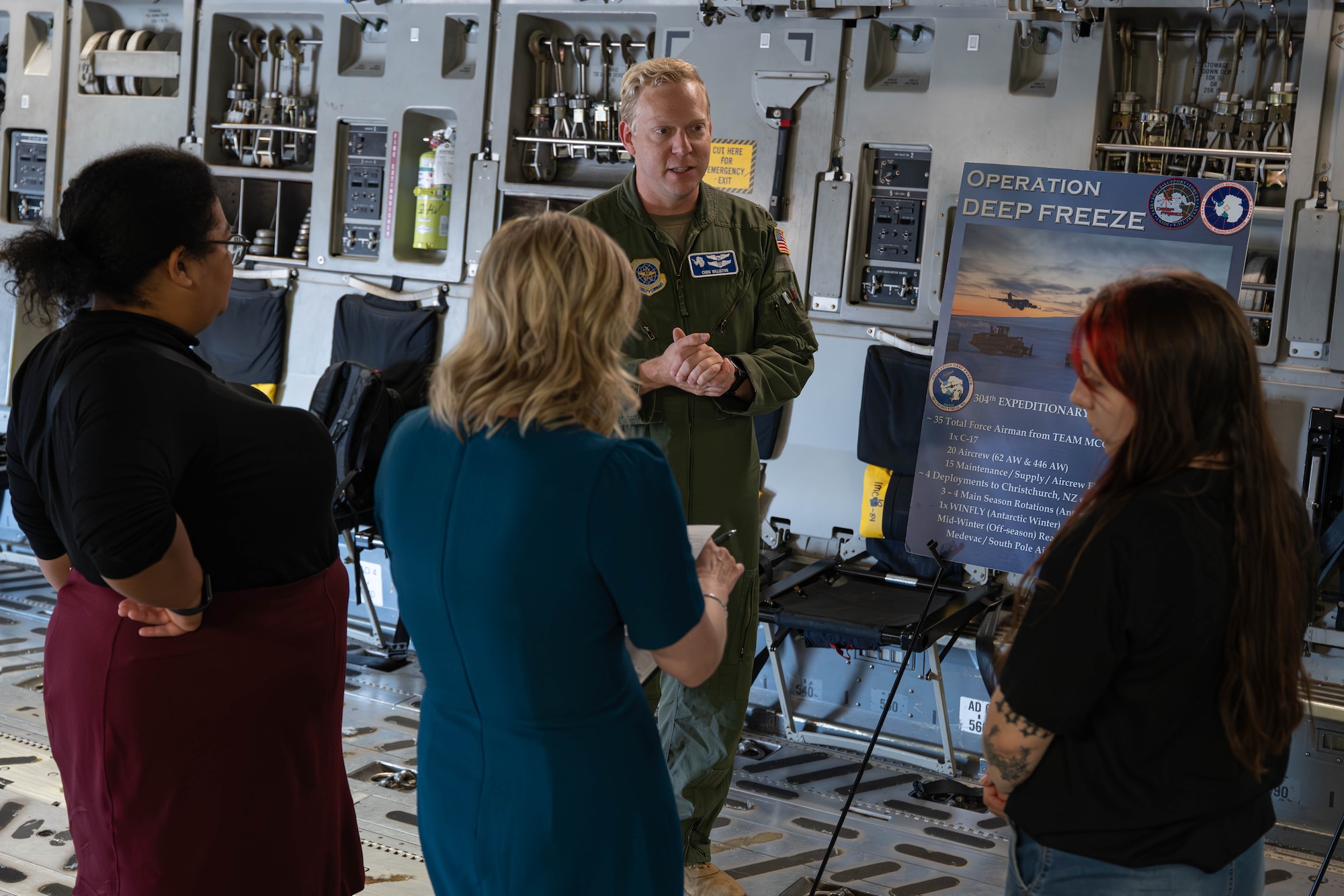 A man speaks to a group inside of a plane