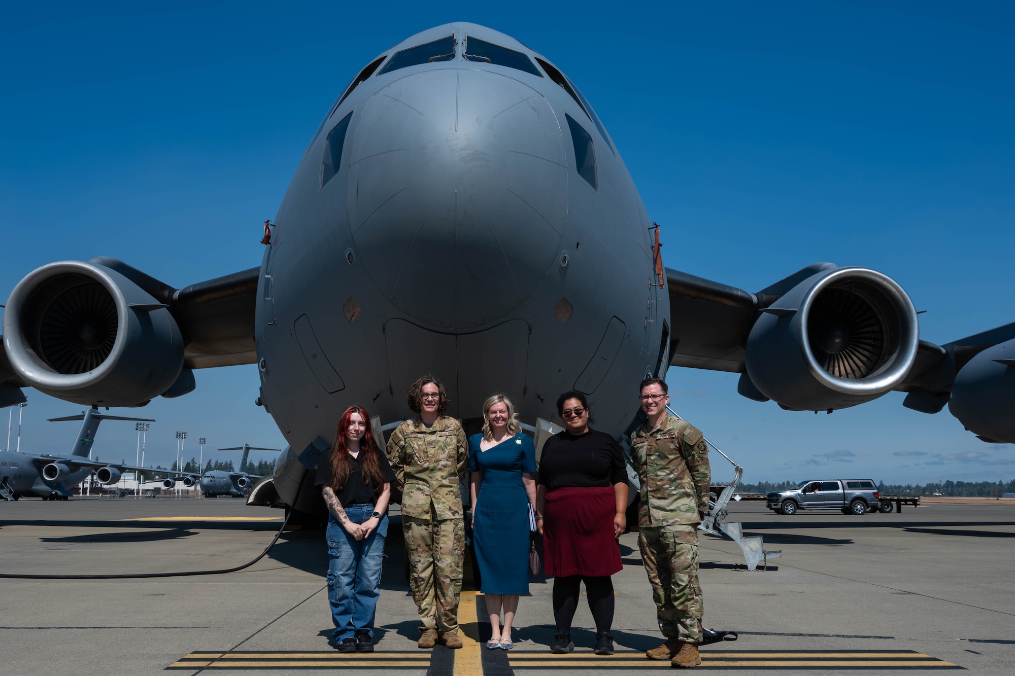 A group poses at the nose of an aircraft.