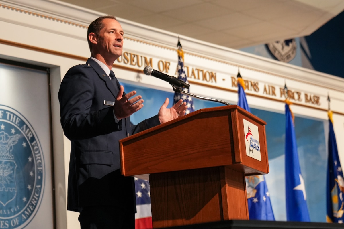 A general holds his hands up while speaking from behind a podium