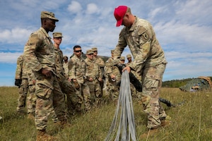 U.S. Army Sgt. Hunter Torres, a parachute rigger assigned to the 173rd Brigade Support Battalion, 173rd Airborne Brigade, demonstrates how to recover a parachute during Exercise Saber Junction 26 at the Joint Multinational Readiness Center in Hohenfels, Germany, Aug. 24, 2026. Saber Junction 26 is an annual exercise designed to assess the readiness of U.S. Army Europe and Africa's permanently assigned brigades, as well as participating Allies and partners. (U.S. Army photo by Sgt. 1st Class Seth Plagenza)