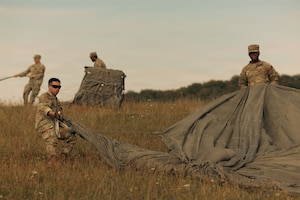 U.S. Soldiers with the 173rd Mobile Brigade Combat Team gather parachutes following an aerial resupply drop during exercise Saber Junction 26 at the Joint Multinational Readiness Center's Hohenfels Training Area, Germany, Aug. 24, 2026. The 7th Army Training Command provides a unique environment in Europe to develop leaders and formations prepared for large-scale combat operations, improving readiness. (U.S. Army photo by Spc. Aubrey Boyle, JMRC Vipers)
