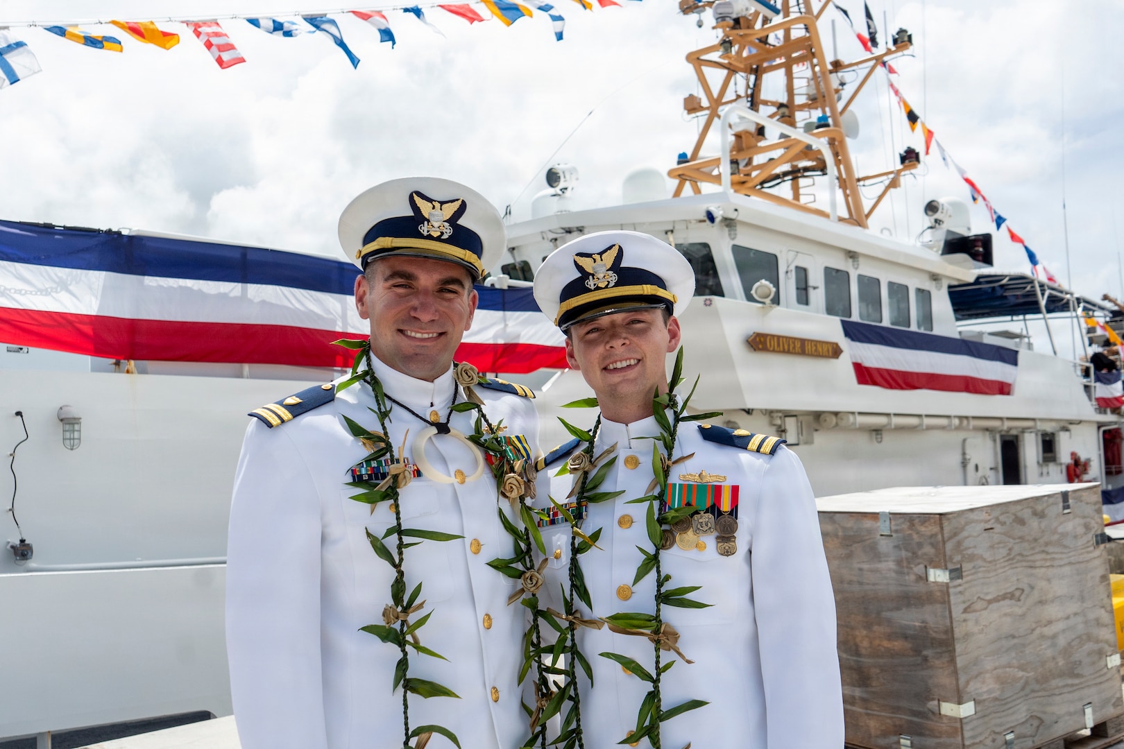 Two Coast Guard officers in dress whites stand in front of Coast Guard cutter