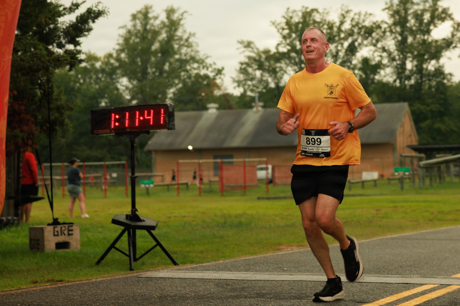 U.S. Marine Corps Sgt. Maj. Liam Williams, the sergeant major of Marine Corps Base Quantico, crosses the finish line during the Quantico 12k at Officer Candidates School on MCB Quantico, Virginia, Aug. 22, 2026. The annual event challenged runners’ individual tenacity as they ran 7.46 miles of trails through the woods of OCS. (U.S. Marine Corps photo by Cpl. Harleigh Faulk)