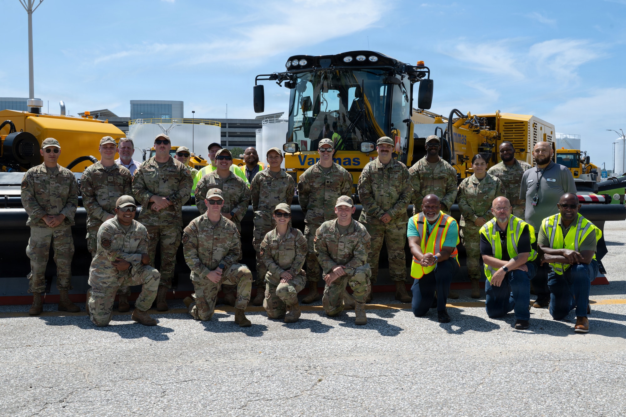 A group of airmen and civilians pose for a group picture. They stand in two rows.