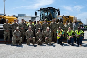 A group of airmen and civilians pose for a group picture. They stand in two rows.