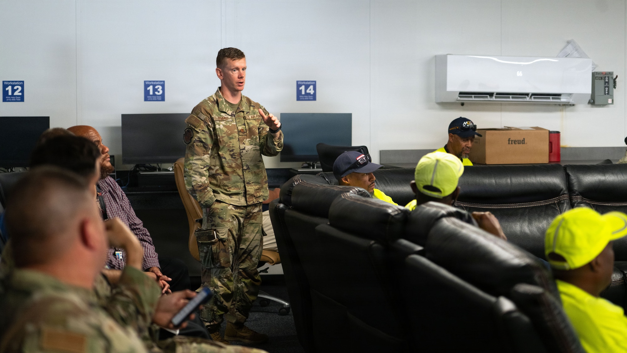 A man stands at the back of a room and speaks.