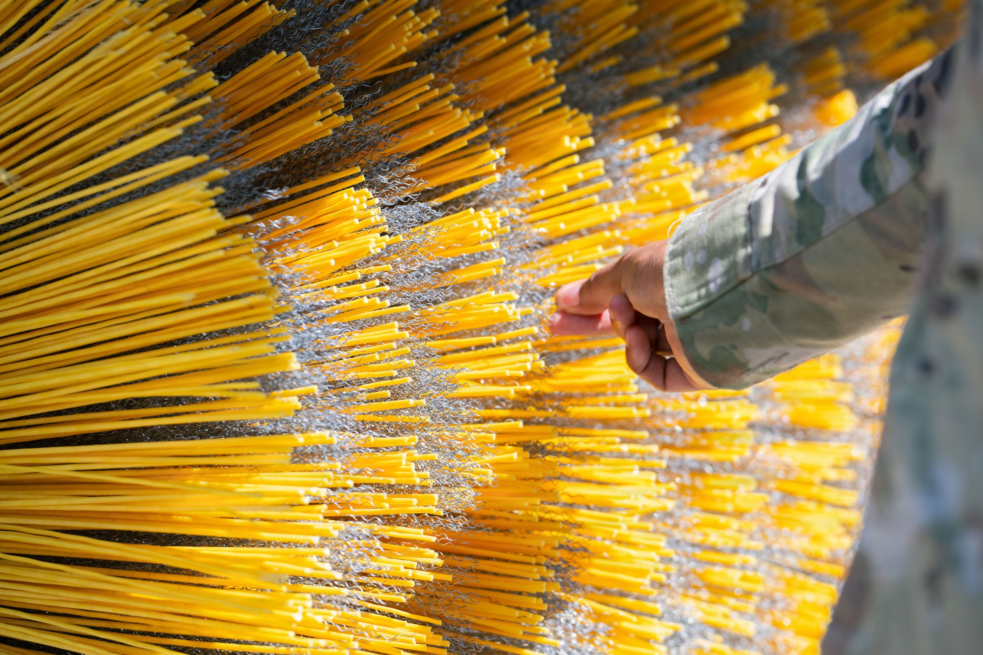 A hand touches a giant yellow broom.