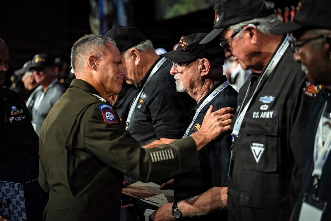 The vice chief of staff of the Army holds the shoulder of a veteran standing in formation with fellow veterans during an award ceremony.