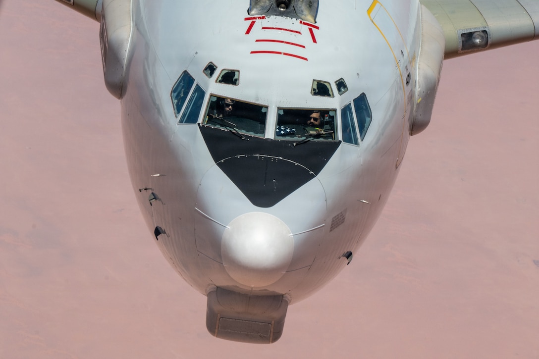 A pilot and co-pilot are in a white aircraft flying in a pink-hued sky.