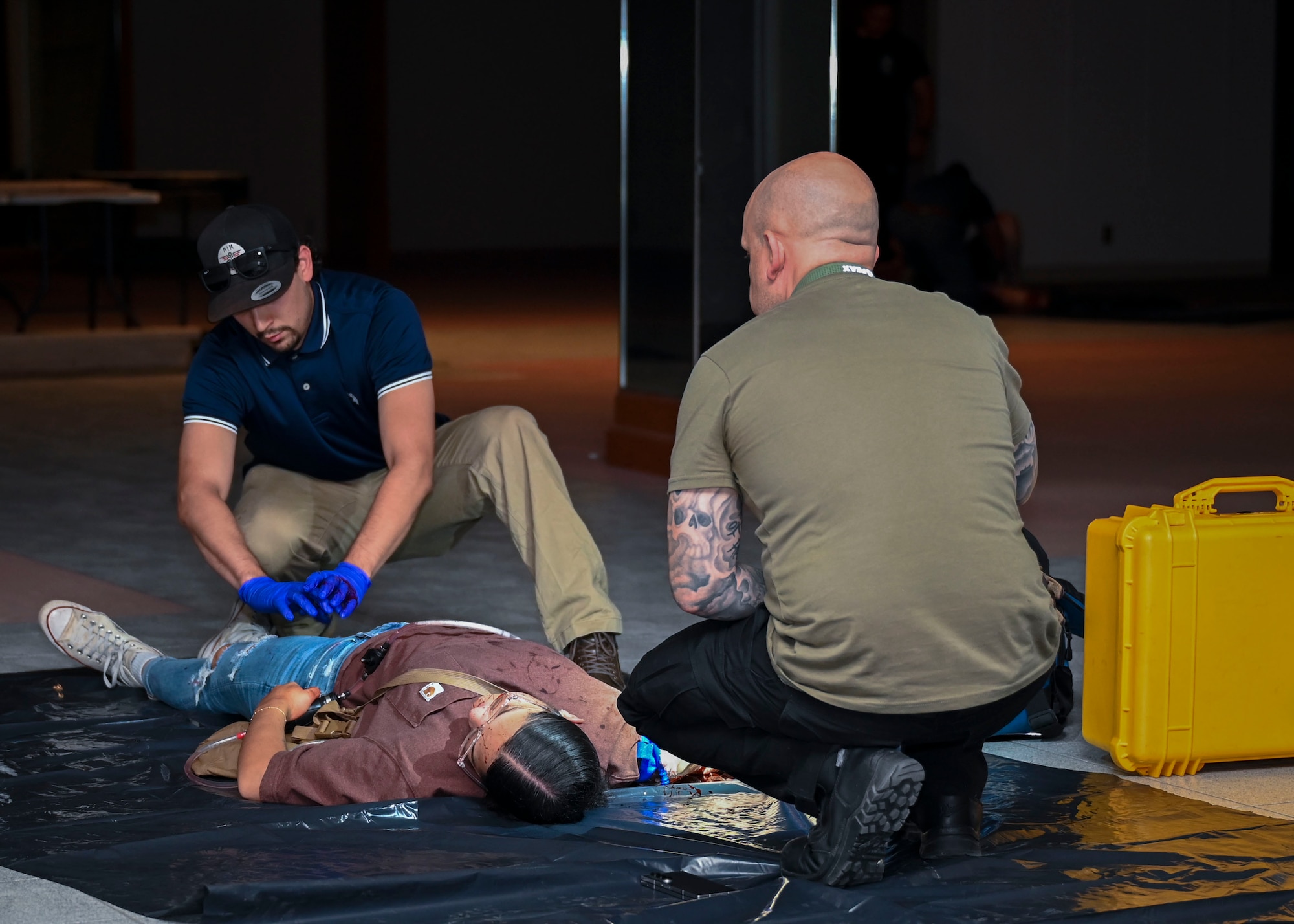 A paramedic attends to a patient's injuries while a person looks on.
