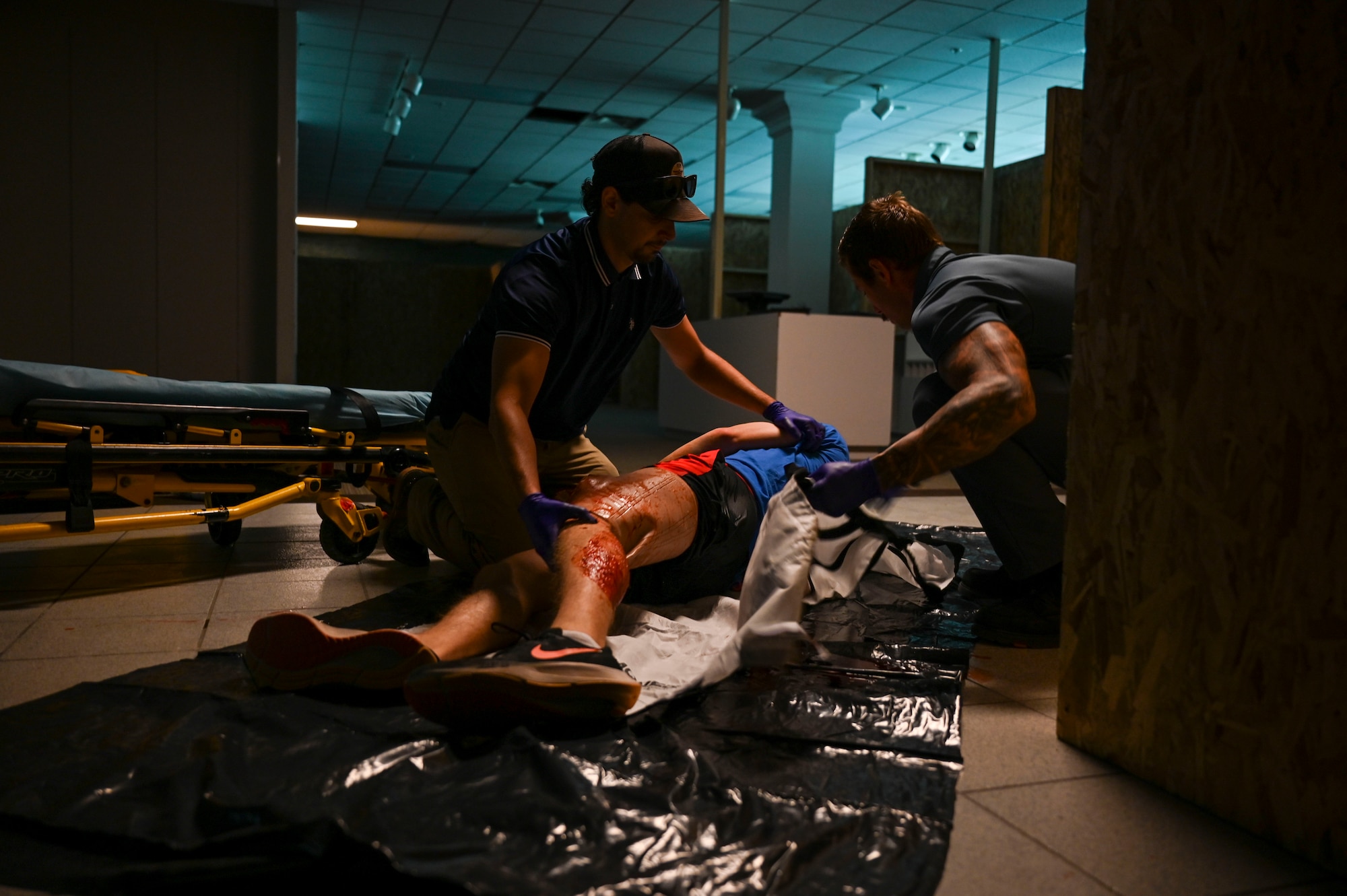 Two paramedic students assist a simulated injured patient that is lying on the ground.
