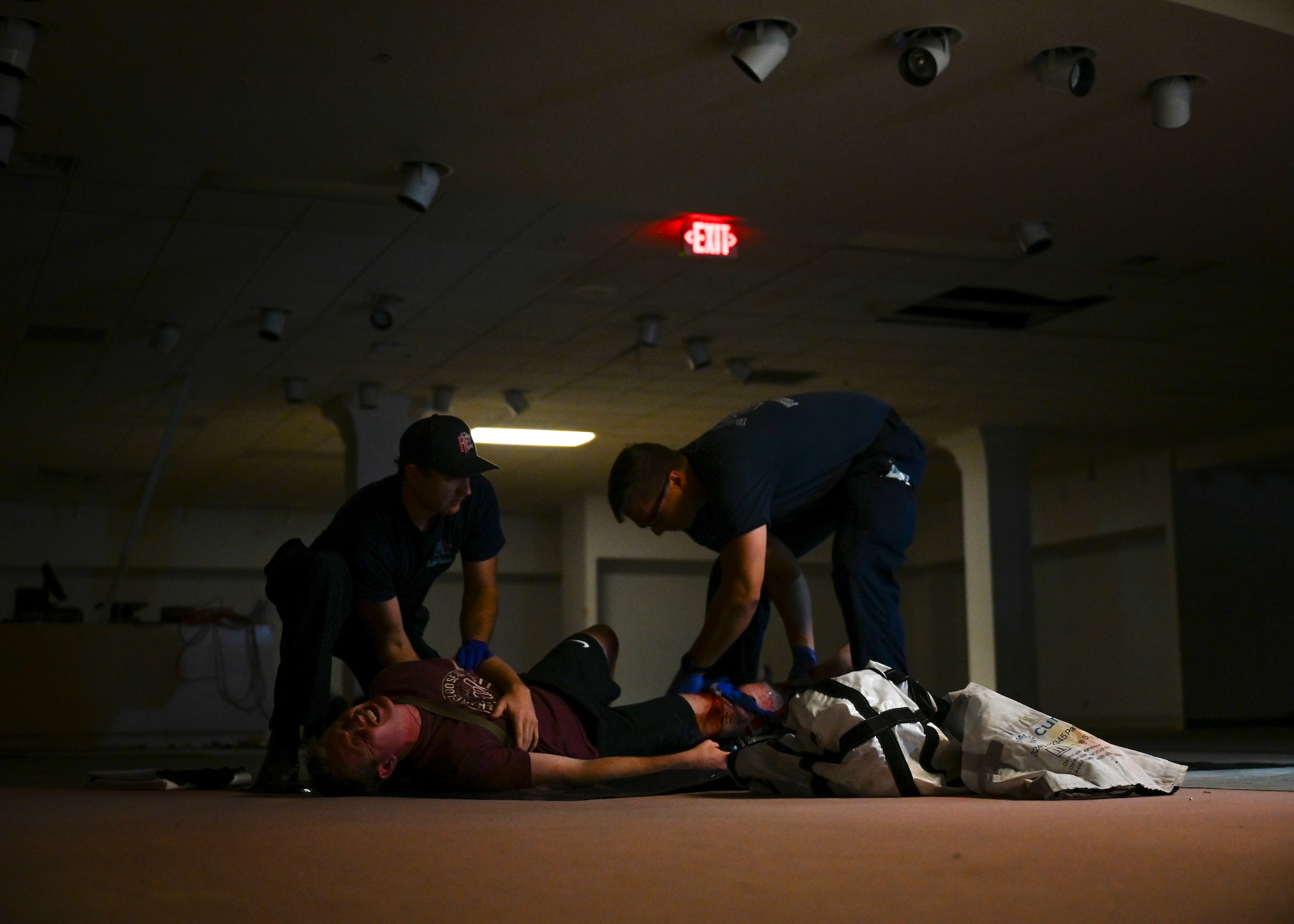 Two paramedics assist a patient that is lying on the ground.